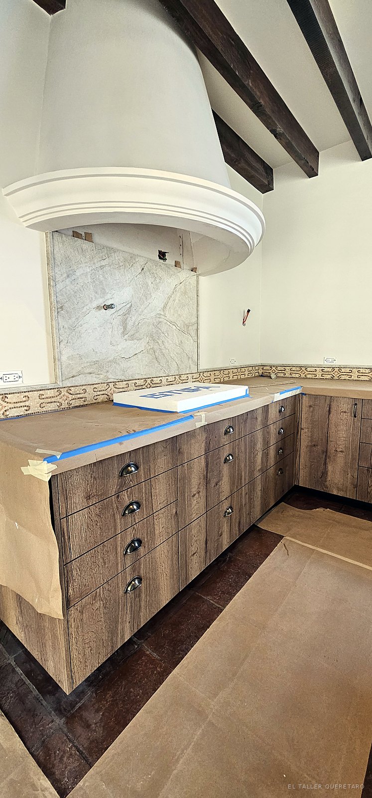 Cocina con campana de obra, cajoneras con jaladeras de concha y vigas de madera