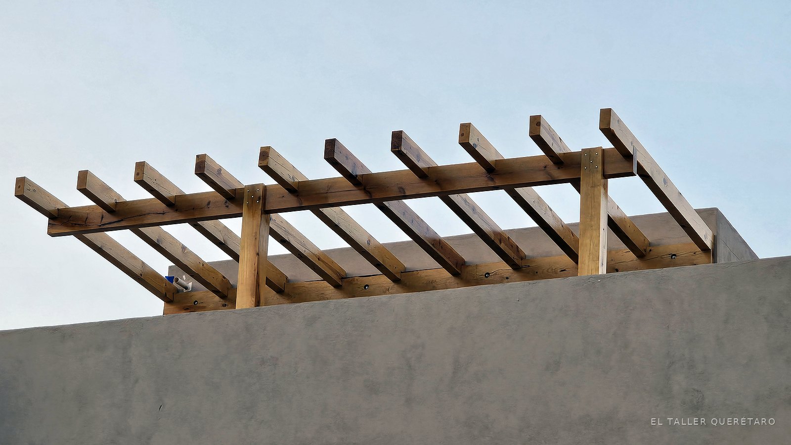Vigas y columnas de la pérgola de madera contra el cielo, proyecto La Madrid