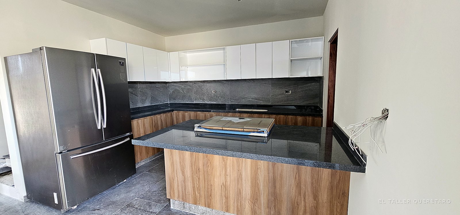 Cocina con isla, bases en nogal, alacenas blancas y cubierta de granito