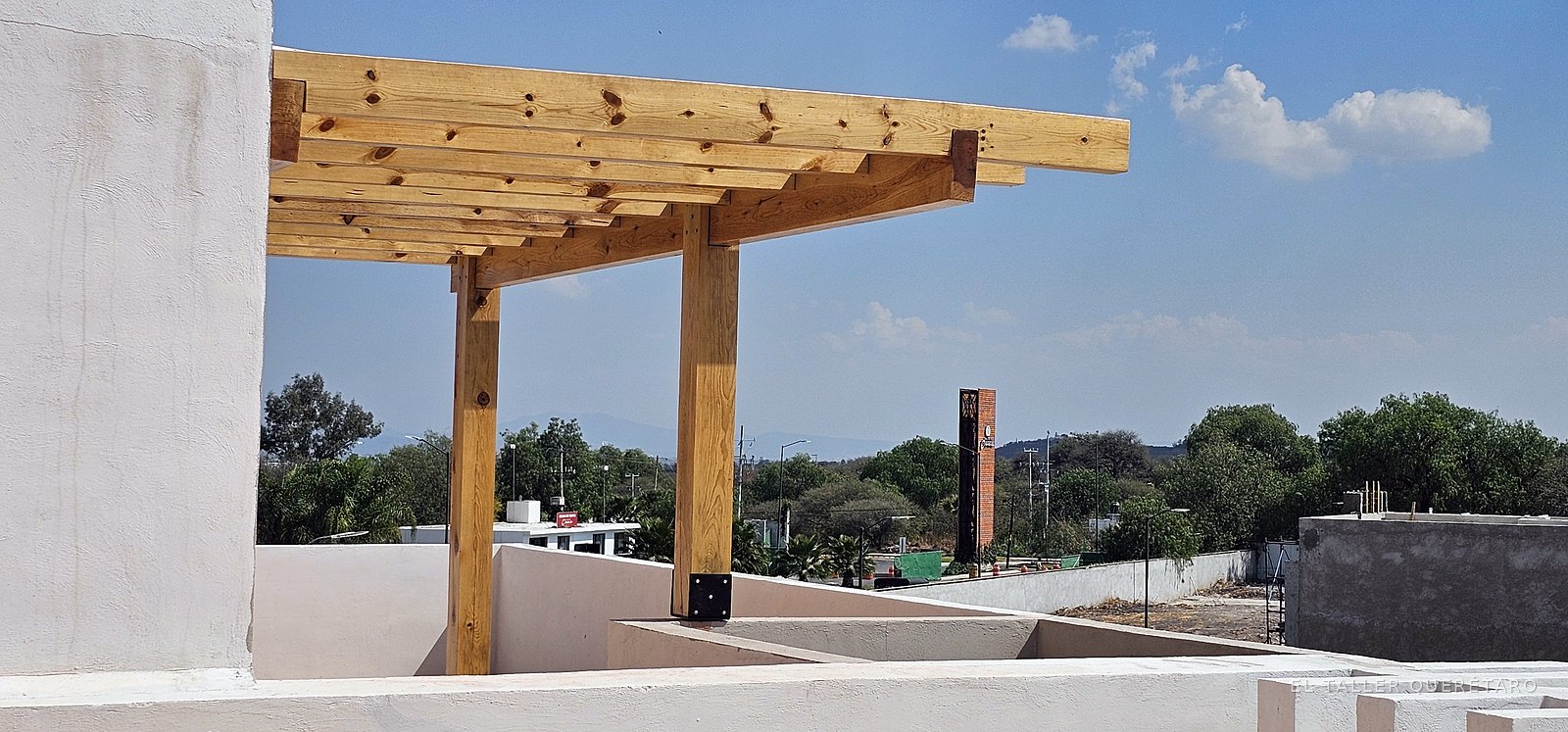 Pérgola de vigas de madera sobre la terraza, con vista al valle