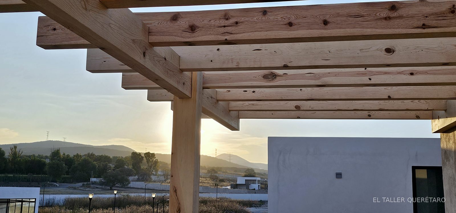 Pérgola de vigas de madera en azotea al atardecer