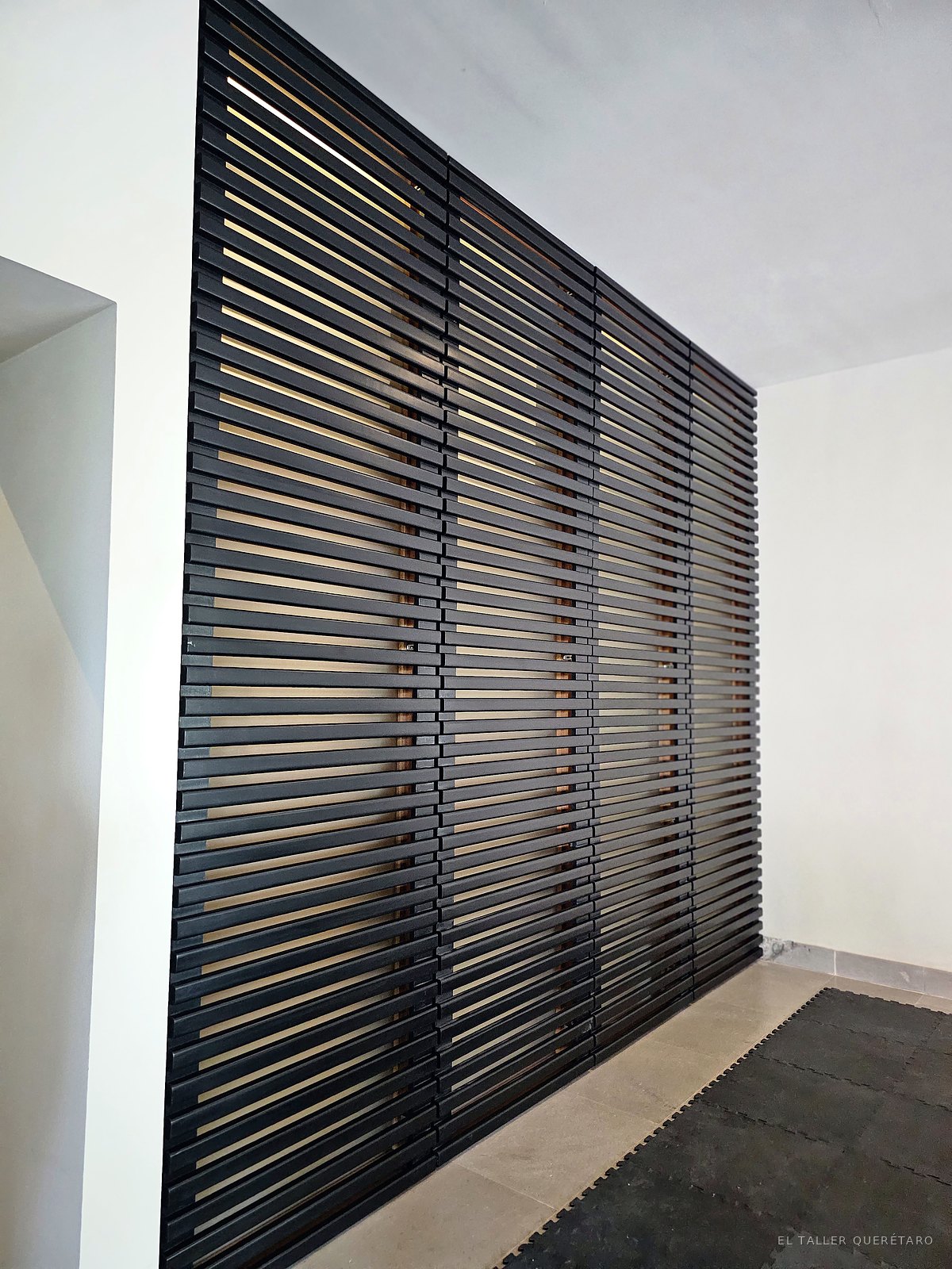 Celosía de listones en negro cubriendo un muro completo