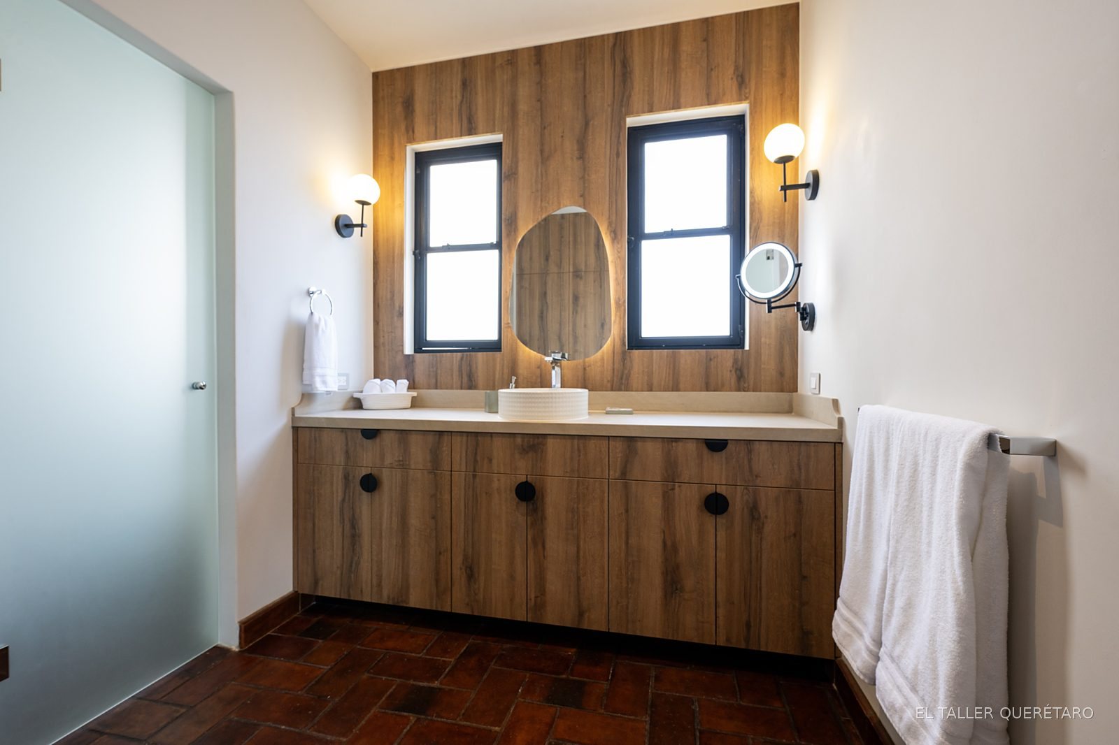 Baño con muro de madera, doble ventana y lavabos