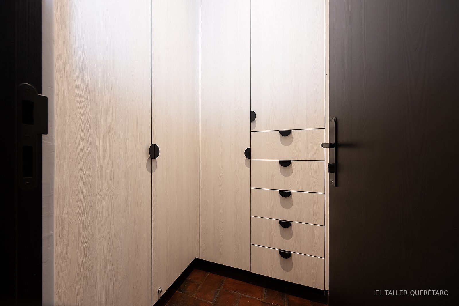 Closet de puertas con jaladeras negras y cajonera