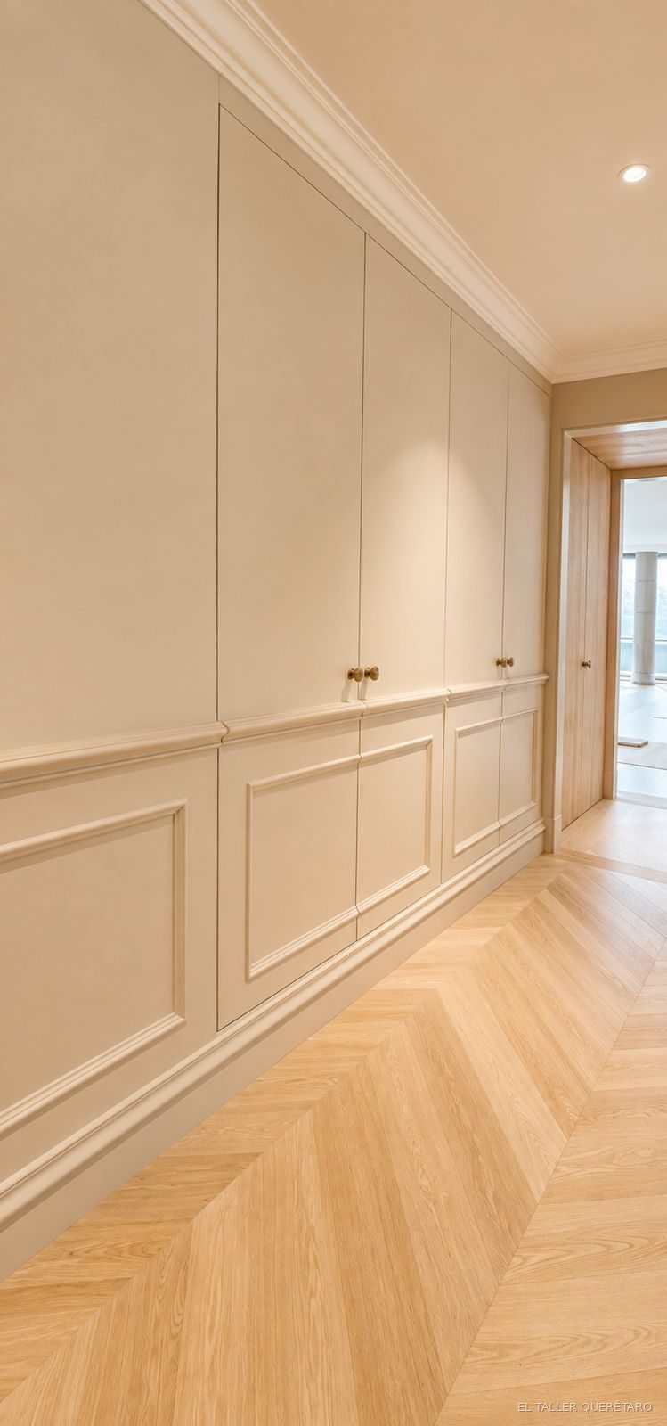 Closet de pasillo con puertas laqueadas en blanco mate y tiradores de latón
